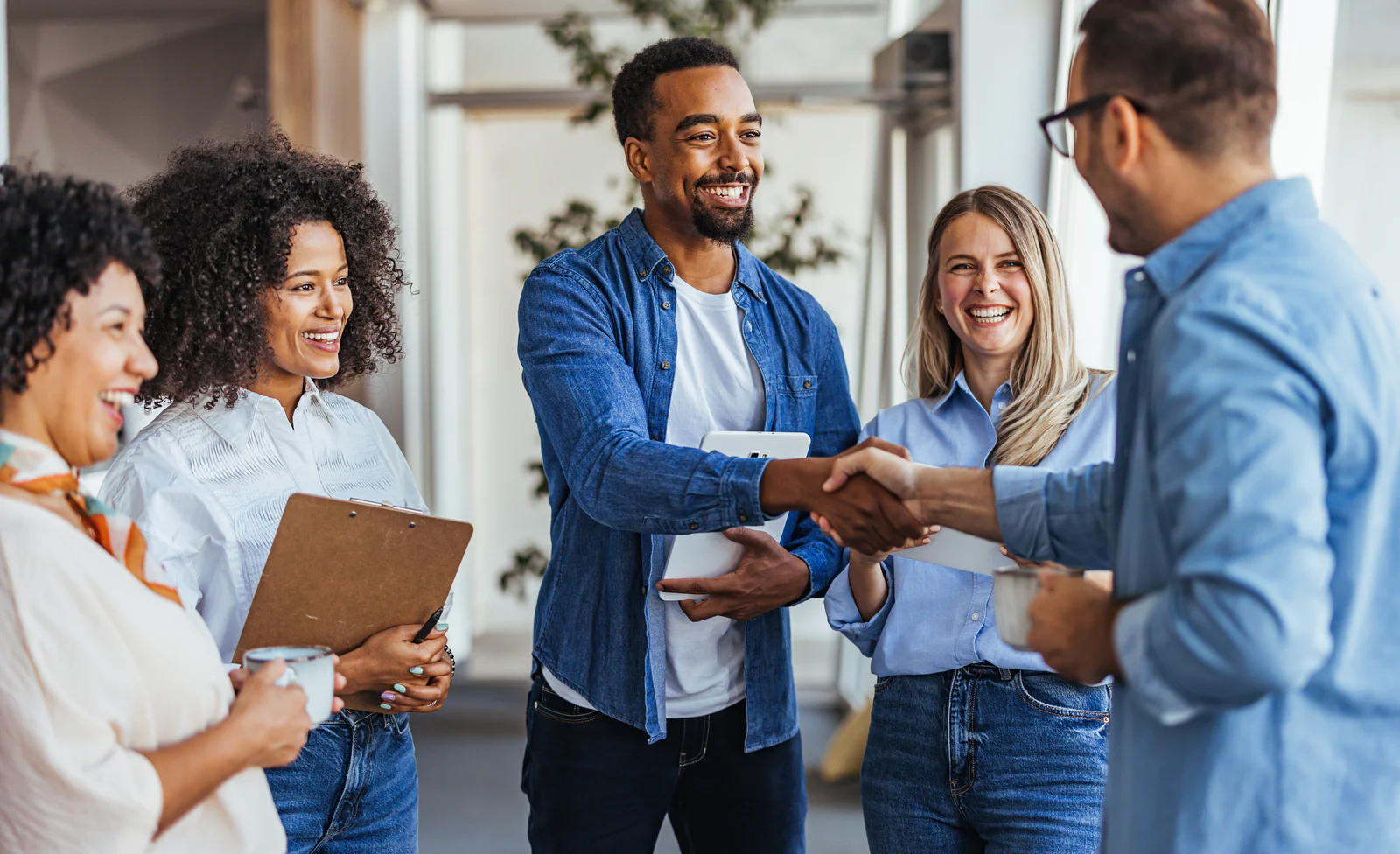 Businesses aren’t just buying tools, they’re building outcomes Colleagues smiling and shaking hands in a modern office environment.