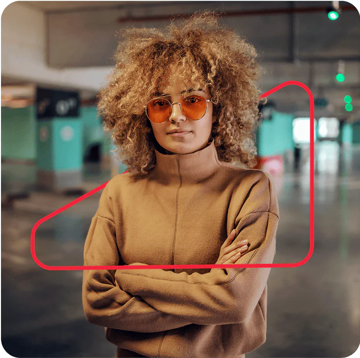 Woman with curly hair and glasses wearing a brown sweater, standing confidently in a parking garage. Woman with curly hair and glasses wearing a brown sweater, standing confidently in a parking garage.