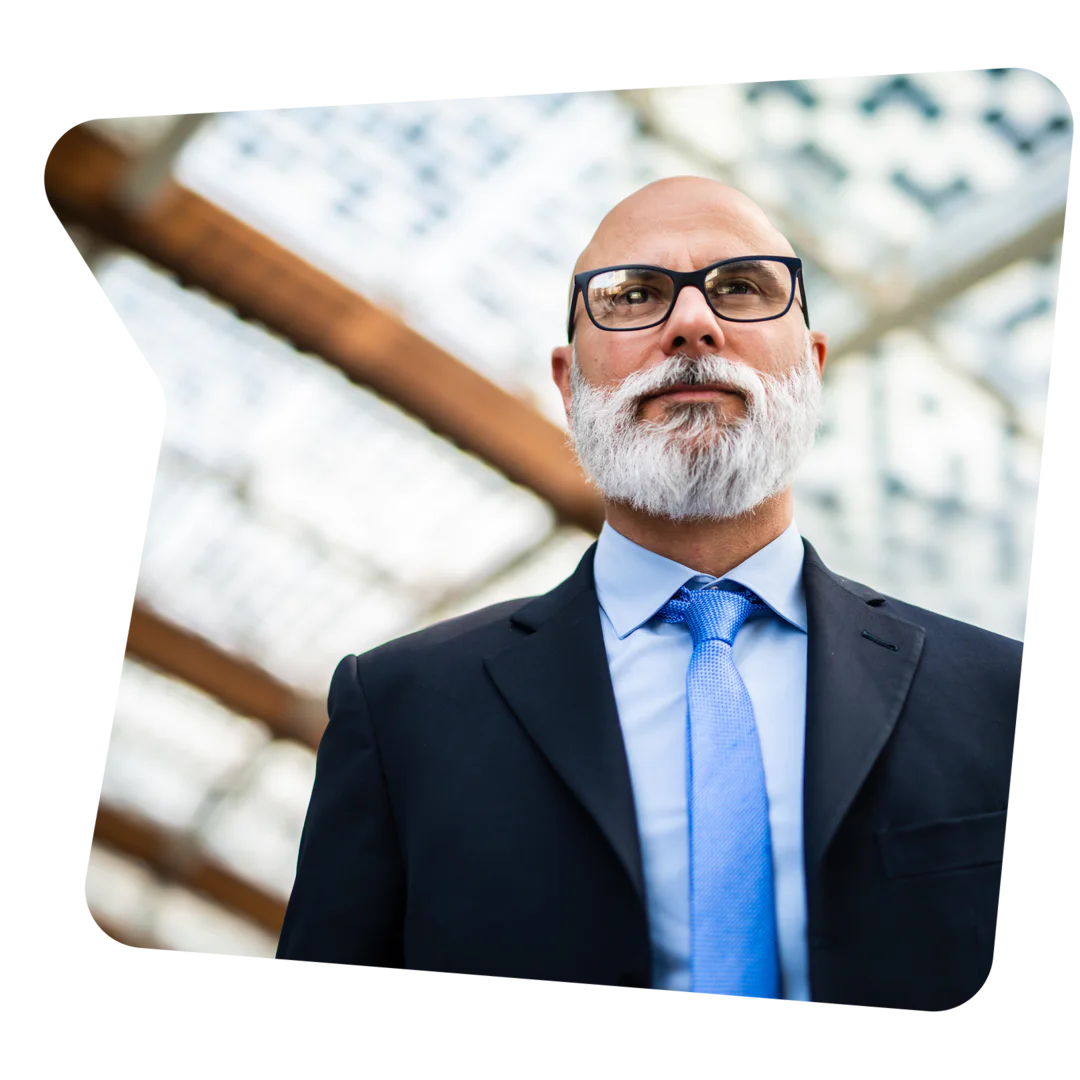 Professional Man in Glasses and Suit with Blue Tie Bald man with a white beard wearing glasses and a suit with a blue tie.