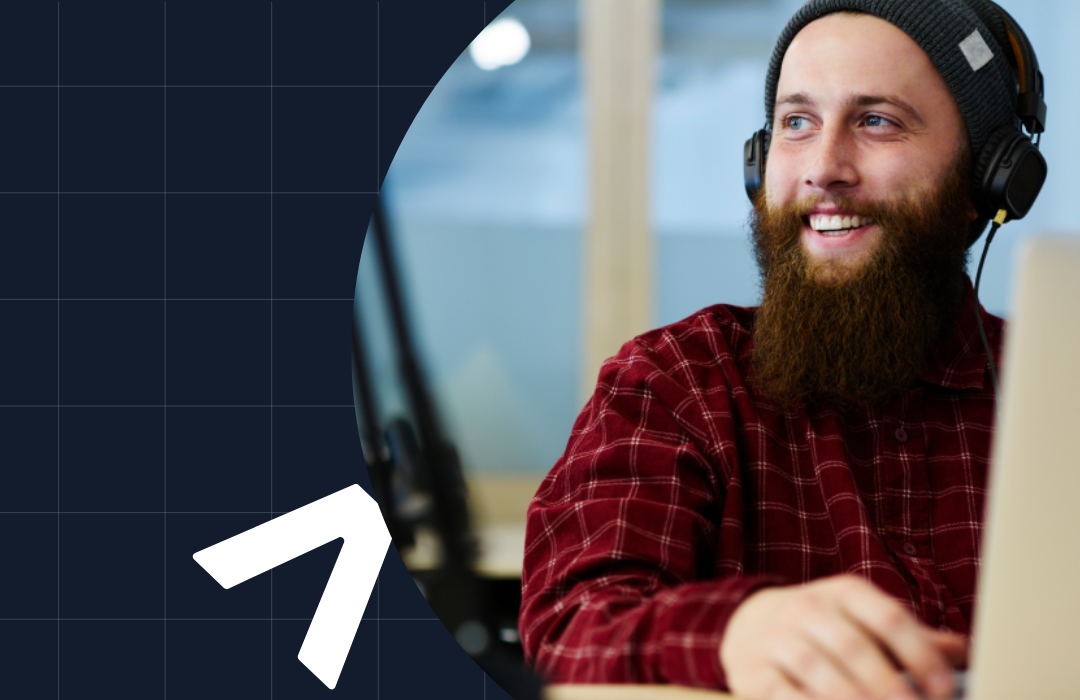 Bearded man in a beanie and headphones smiles while using a laptop, with an arrow graphic on the left.