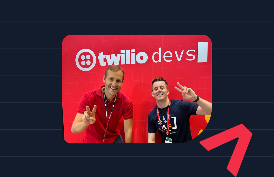 Two men posing with peace signs at a Twilio devs booth featuring a red background and Twilio logo.