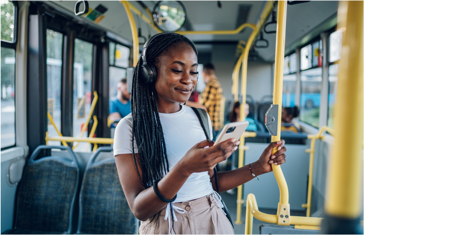 ** Woman with headphones using her phone while standing on a bus