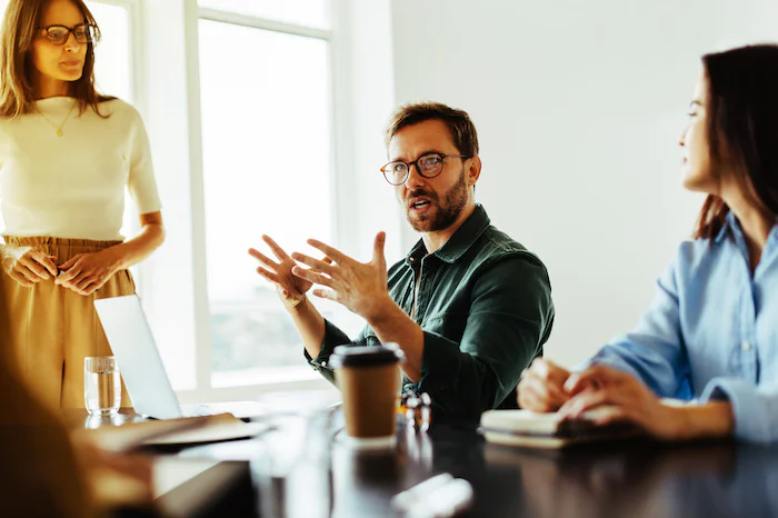 Three colleagues engaged in a discussion around a conference table.