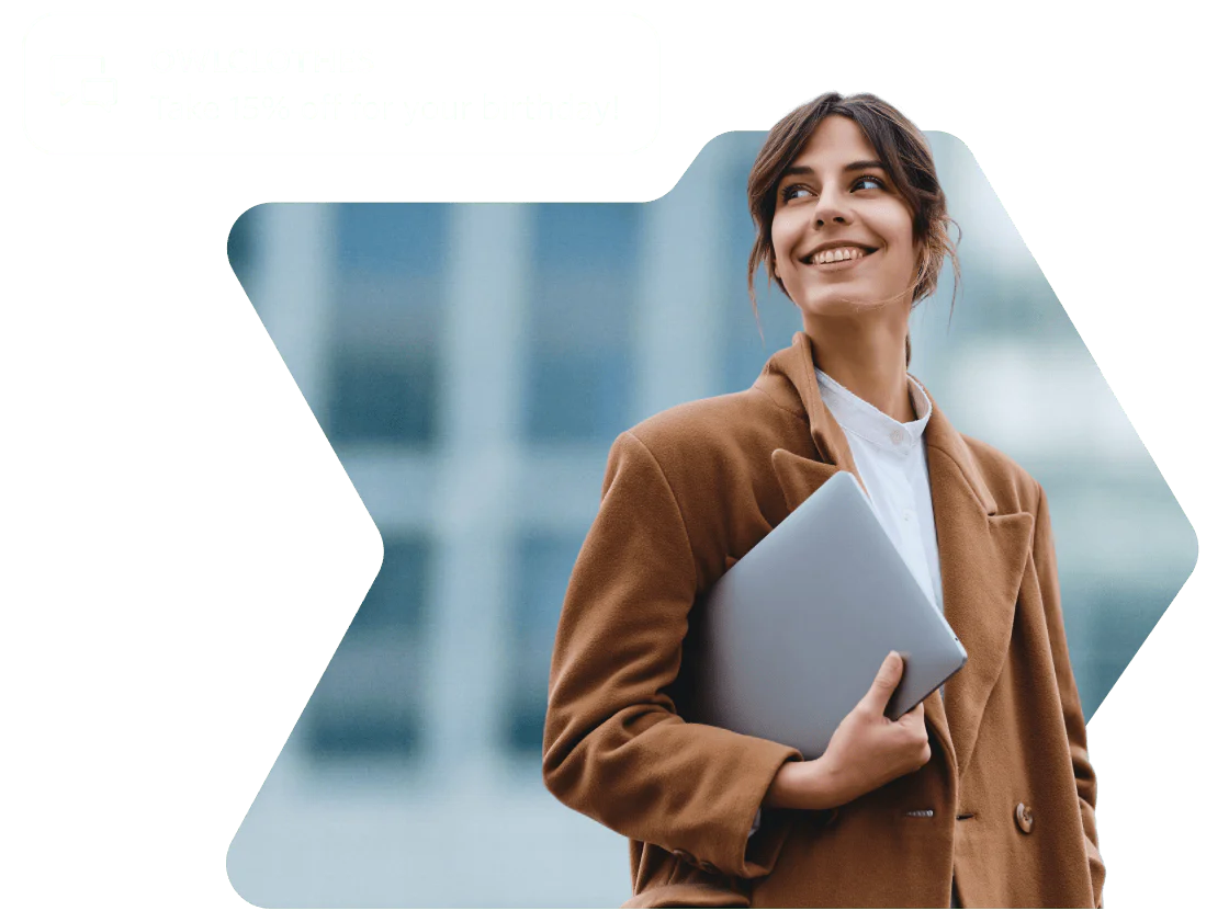 Woman in brown coat smiling and holding a laptop with a birthday discount notification from OWLCLOTHES Woman in brown coat smiling and holding a laptop with a birthday discount notification from OWLCLOTHES