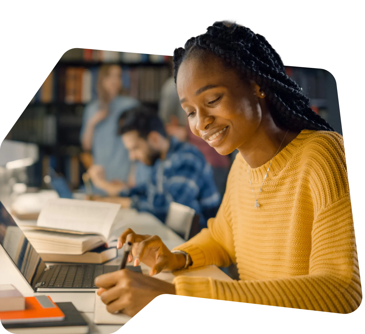 Building customer trust by protecting data Woman in yellow sweater studying at a library table with a laptop and books.