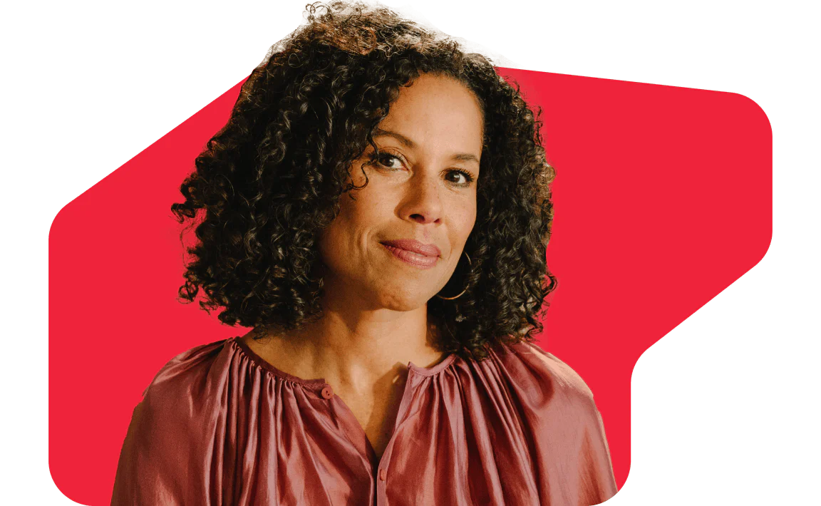 Woman with curly hair in front of a red geometric background Woman with curly hair wearing a pink blouse against a red geometric background