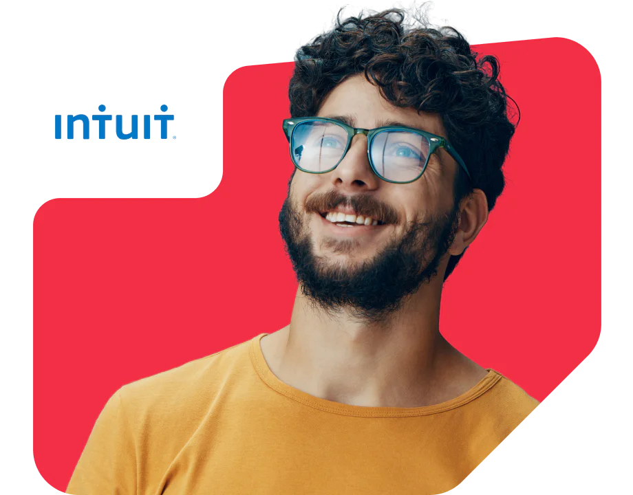 Intuit sign up verification using Twilio Verify Smiling man talking on phone while using laptop, with Intuit logo in the corner.