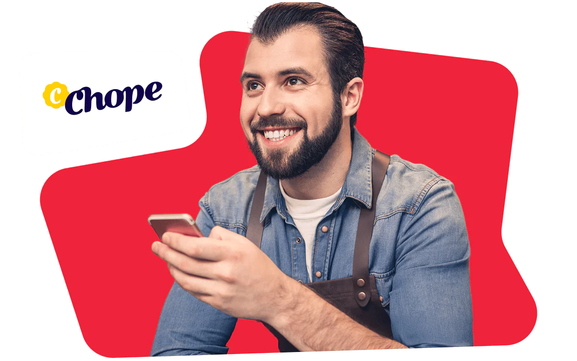 Smiling man holding a phone with Chope logo on a red background Bearded man in a denim shirt, holding a phone, Chope logo in the top left, red background